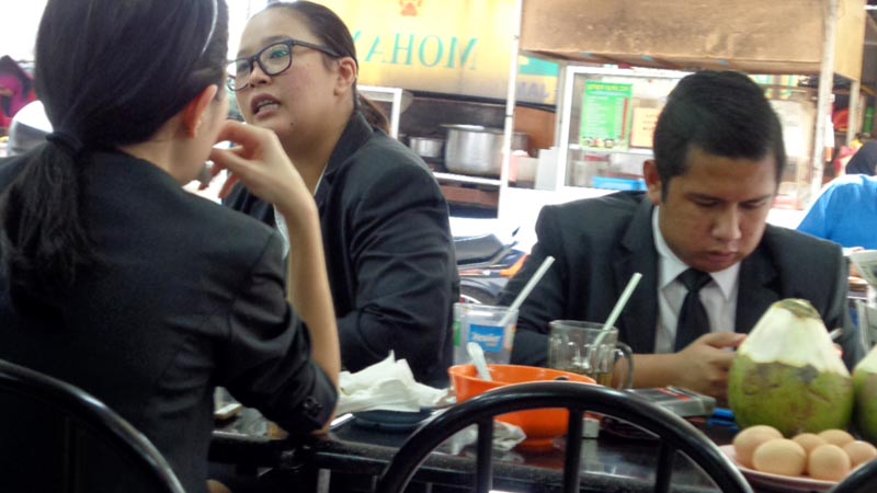 guys in business suits can be seen eating in hawker food stalls